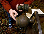Person in red sweater points to sphere shaped wooden desk foot and holds smaller sphere shaped wooden foot in other hand.